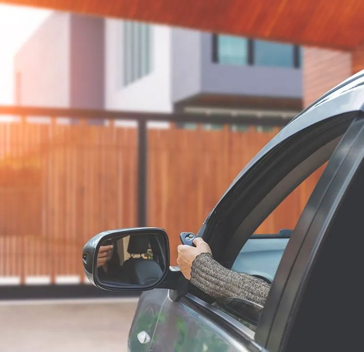 A driver opening an automated gate by remote from the car.